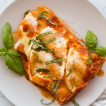 two cheese cannelloni on a grey plate with fresh basil