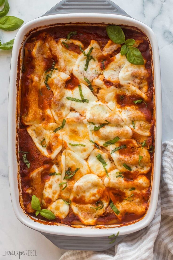 overhead image of baking dish with cheese cannelloni and fresh basil