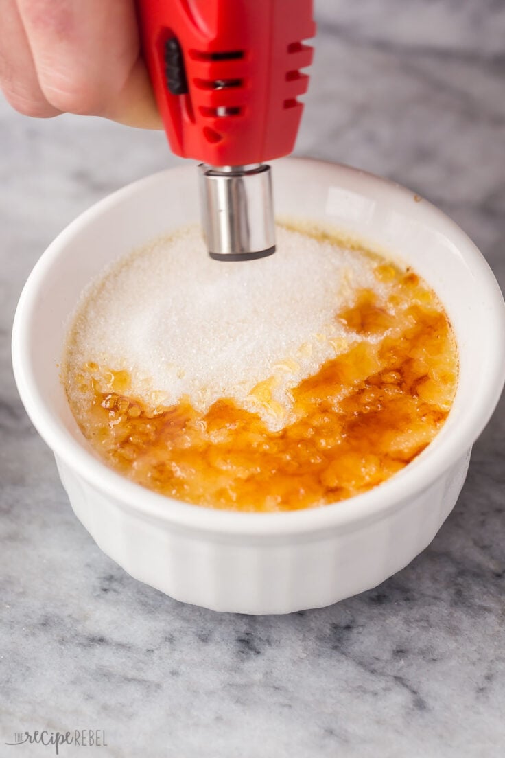 torch being used to brown sugar on top of creme brulee