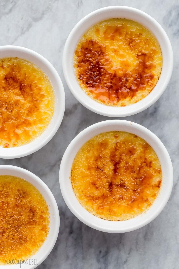 This Crème Brûlée Recipe results in a rich, smooth, and silky custard base that's finished off with a layer of crunchy caramelized sugar! It's an impressive and decadent dessert that's deceivingly easy to make! #dessert #recipes | easy dessert recipe | holiday | christmas dessert | thanksgiving dessert | egg yolks | cream | easy recipe overhead image of four ramekins of creme brulee