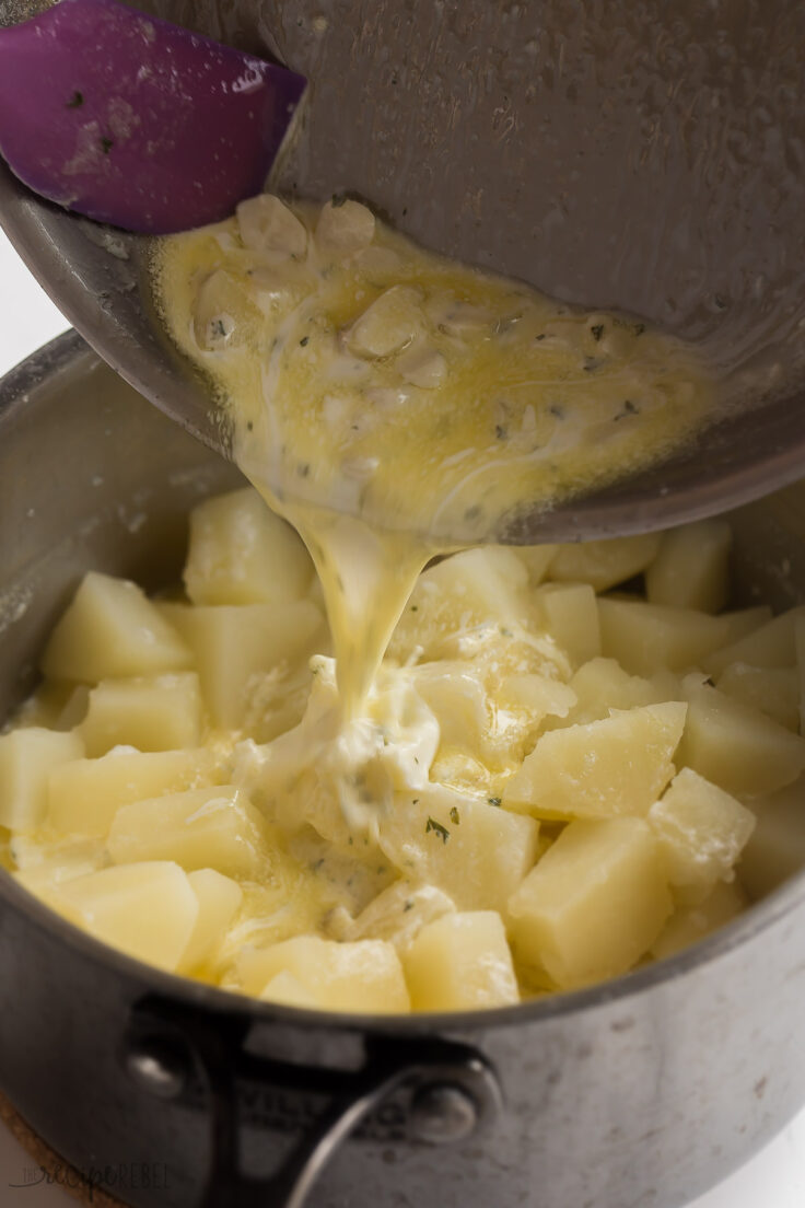 melted butter and cream being poured onto cooked potatoes