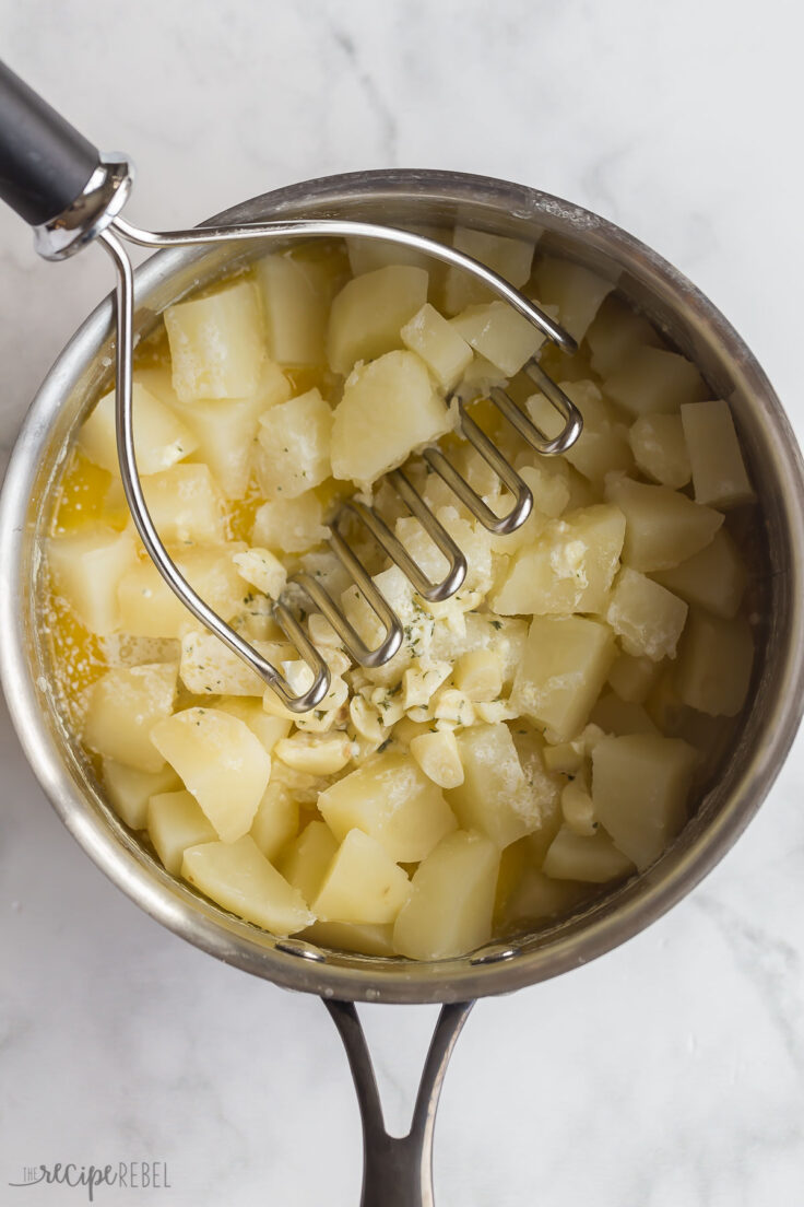 potato masher mashing garlic mashed potatoes in pot