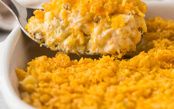 close up image of metal spoon scooping hashbrown casserole