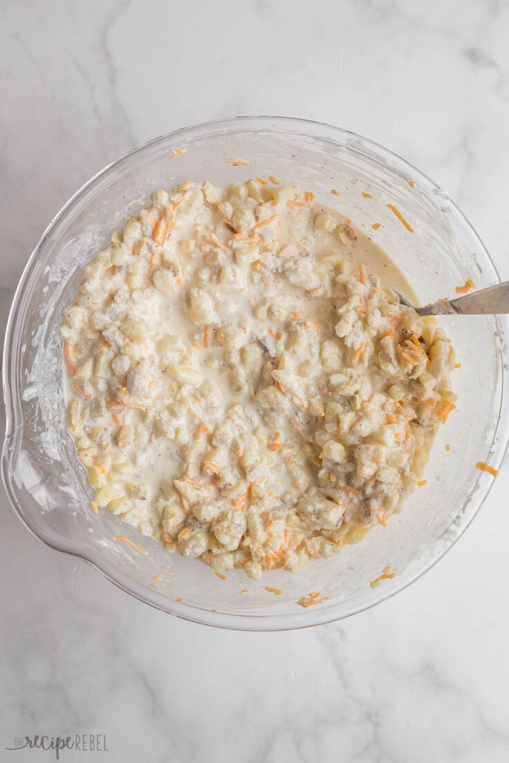 hashbrown casserole ingredients stirred together in glass bowl