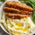 square image of three slices of instant pot meatloaf on mashed potatoes