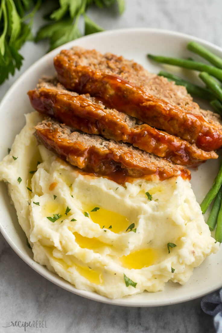 close up image of meatloaf slices stacked on mashed potatoes