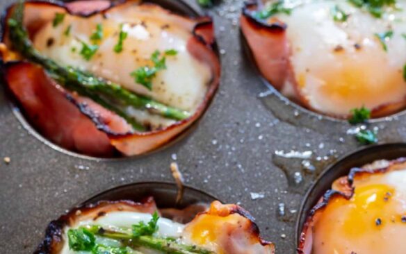 ham and egg cups in muffin tip with pieces of asparagus on top