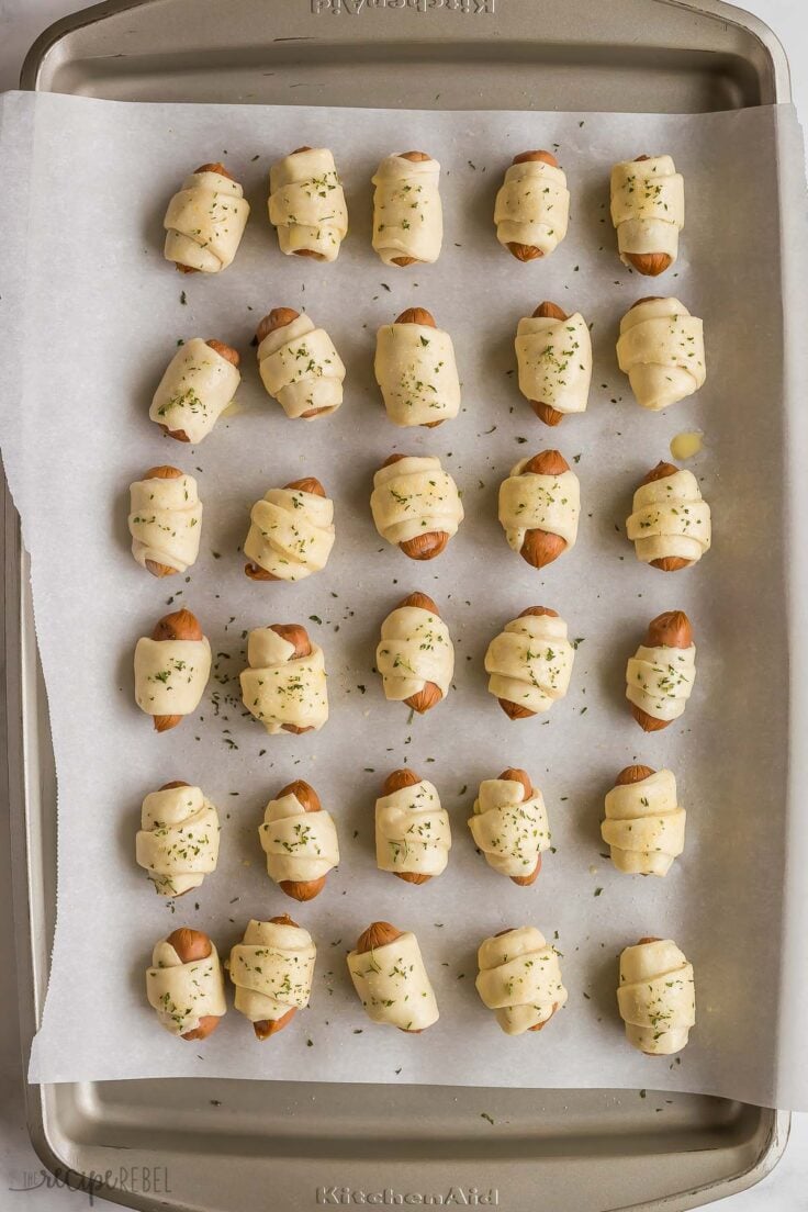 overhead image of pigs in a blanket on a baking sheet ready to bake