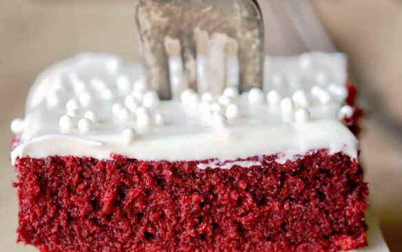 stack of two red velvet cake bars with frosting and fork stuck in