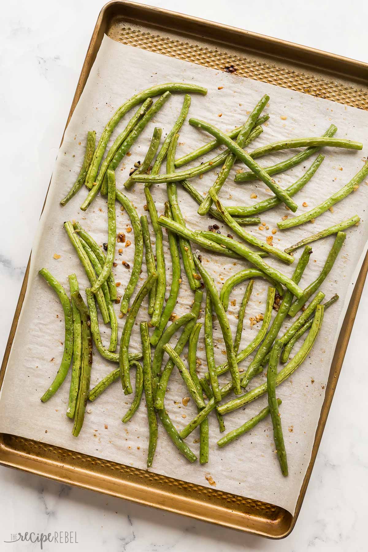 overhead image of roasted green beans on parchment on baking sheet