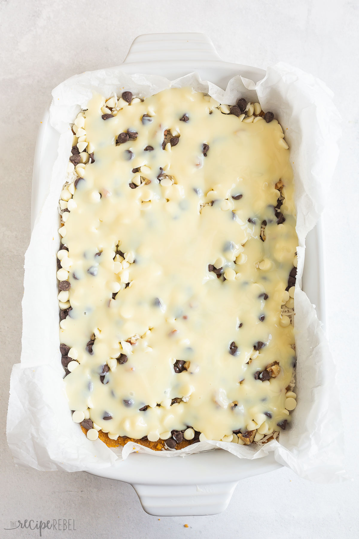 sweetened condensed milk poured over chocolate chips in baking dish.