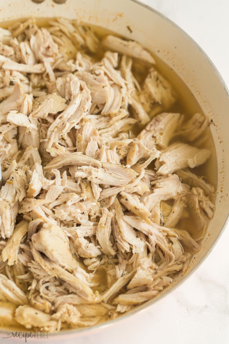 close up image of shredded chicken in white skillet with juices