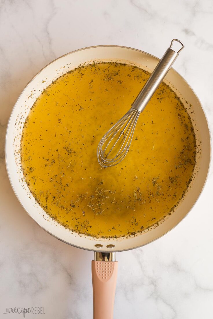 broth and seasonings in a white skillet ready to make shredded chicken