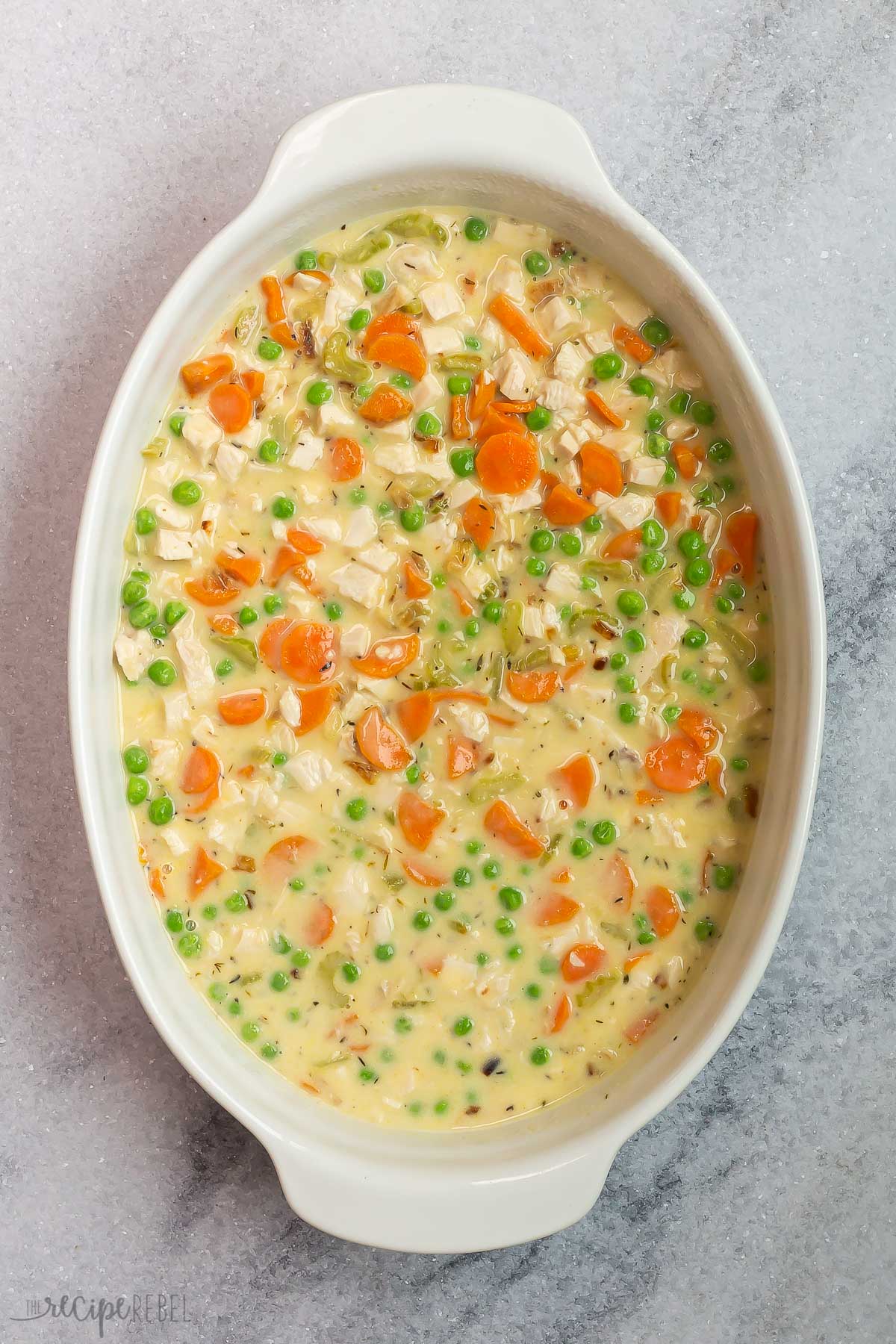 turkey vegetables and gravy in white baking dish ready for topping.