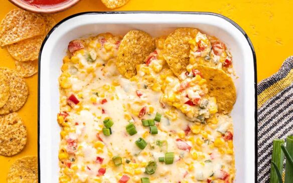 Overhead view of hot corn dip with a few tortilla chips