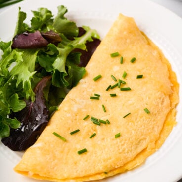 close up image of omelette on plate with greens on the side