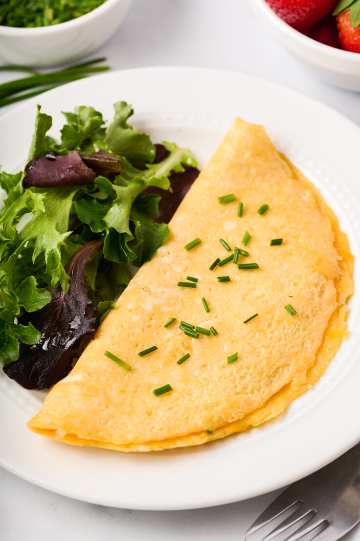 close up image of omelette on plate with greens on the side