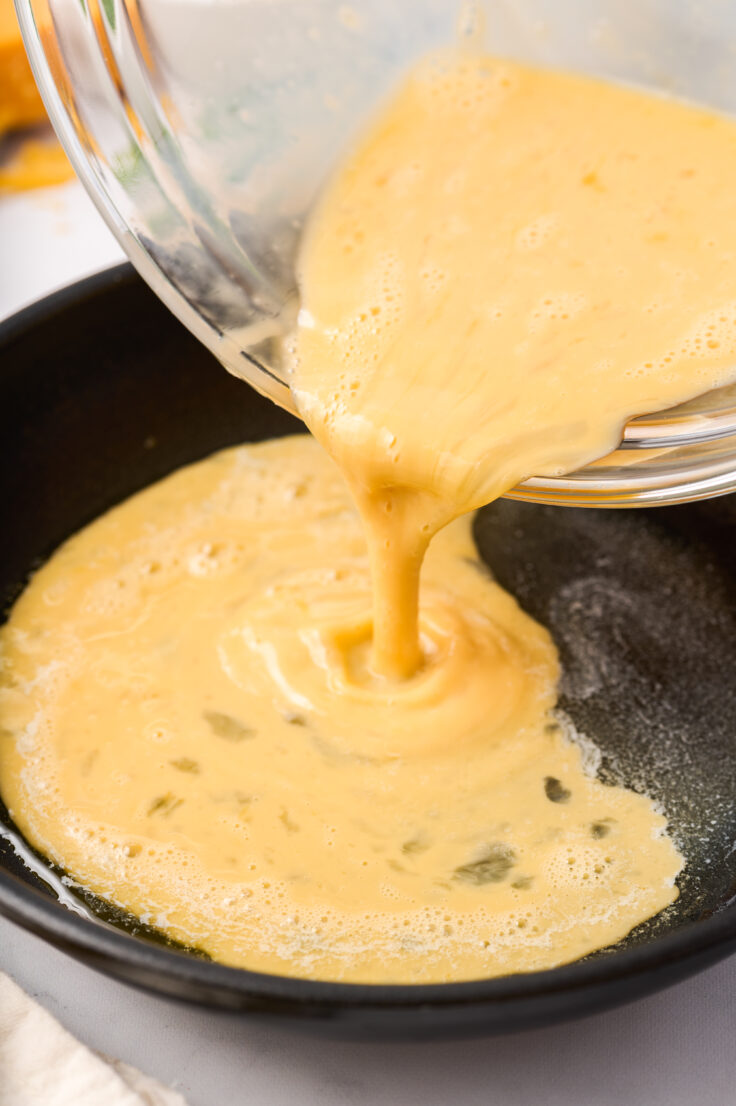omelette mixture being poured into black skillet