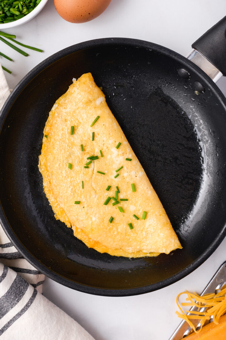 finished omelette in black skillet with chives on top