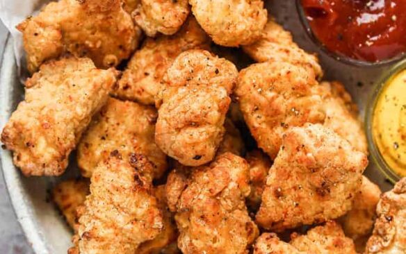 Air fryer chicken nuggets on a platter with dipping sauces.