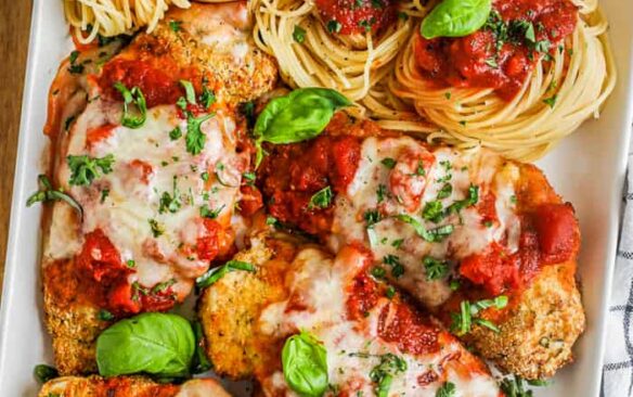 Chicken parmesan served over a bed of spagetti pasta with sauce.