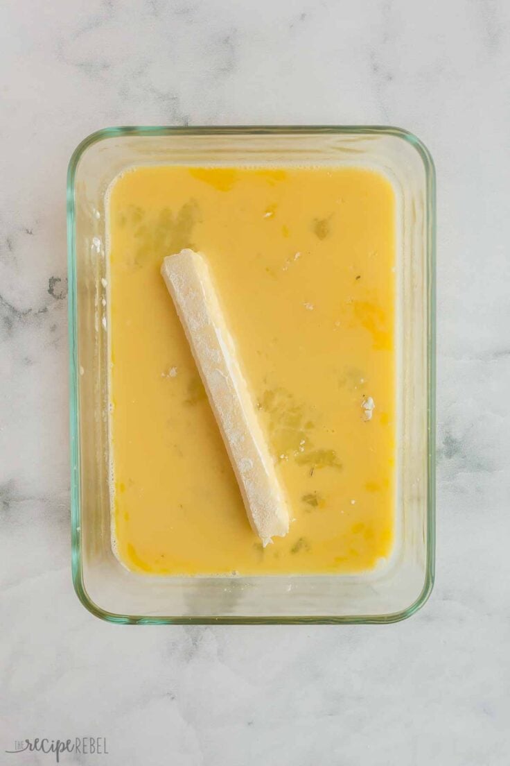 flour coated cheese string being dipped in egg mixture