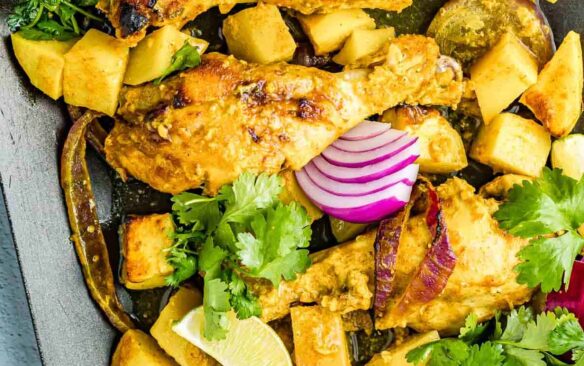 Air fryer tandoori chicken served with potatoes and red onions.