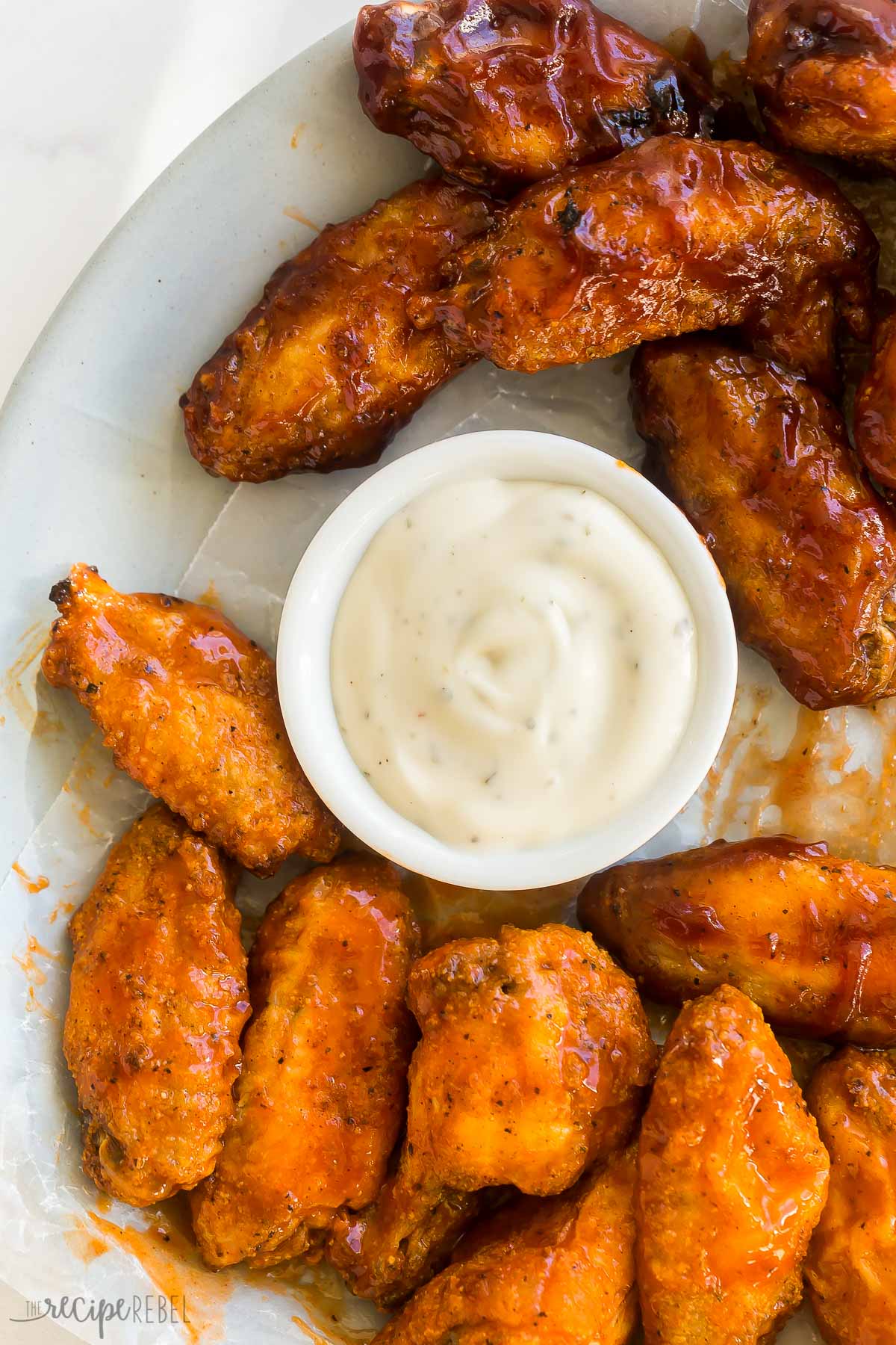 close up image of baked chicken wings in two sauces with ranch dipping sauce