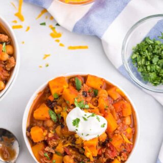 A bowl of butternut squash and turkey chili topped with sour cream.