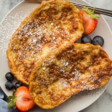 overhead image of two slices of french toast on grey plate with fresh berries