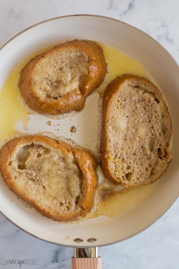 three slices of french toast being cooked in a white skillet