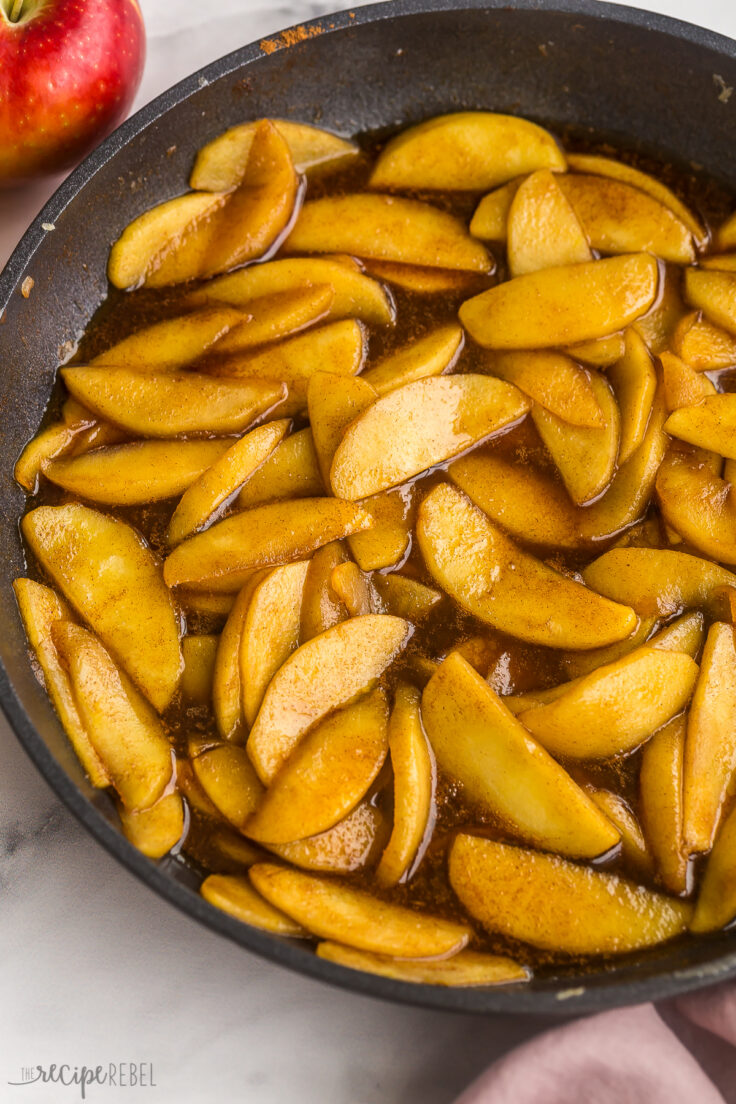 This Fried Apples recipe is my version of classic southern fried apples! This recipe takes 15 minutes to make, requires just 5 ingredients, and results in tender apples smothered in a sweet brown sugar glaze. #apples #recipe #recipes | dessert recipe | breakfast recipe | cinnamon apples | cooked apples | brunch | cosmic crisp close up image of fried apples in black skillet