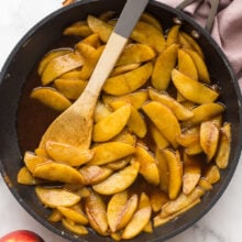 overhead image of fried apples in a black skillet with a wooden spoon