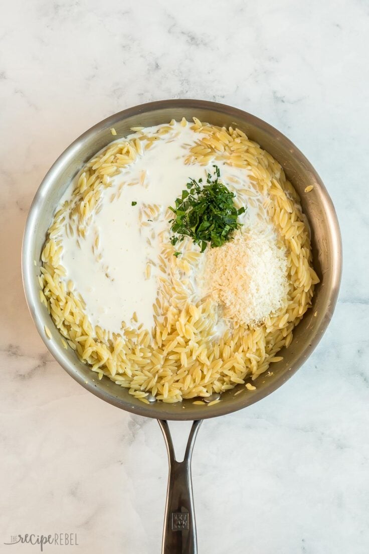 cream parmesan and fresh parsley added to orzo in pan