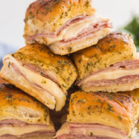 ham sliders stacked up tall on a white plate