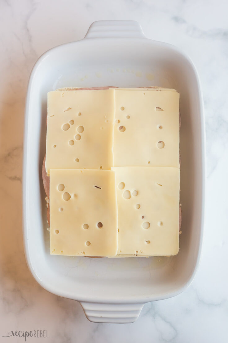 swiss cheese slices layered on top of ham for sliders