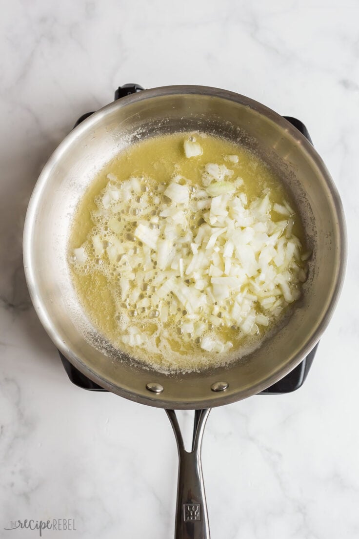 onion being cooked in butter in stainless steel pan