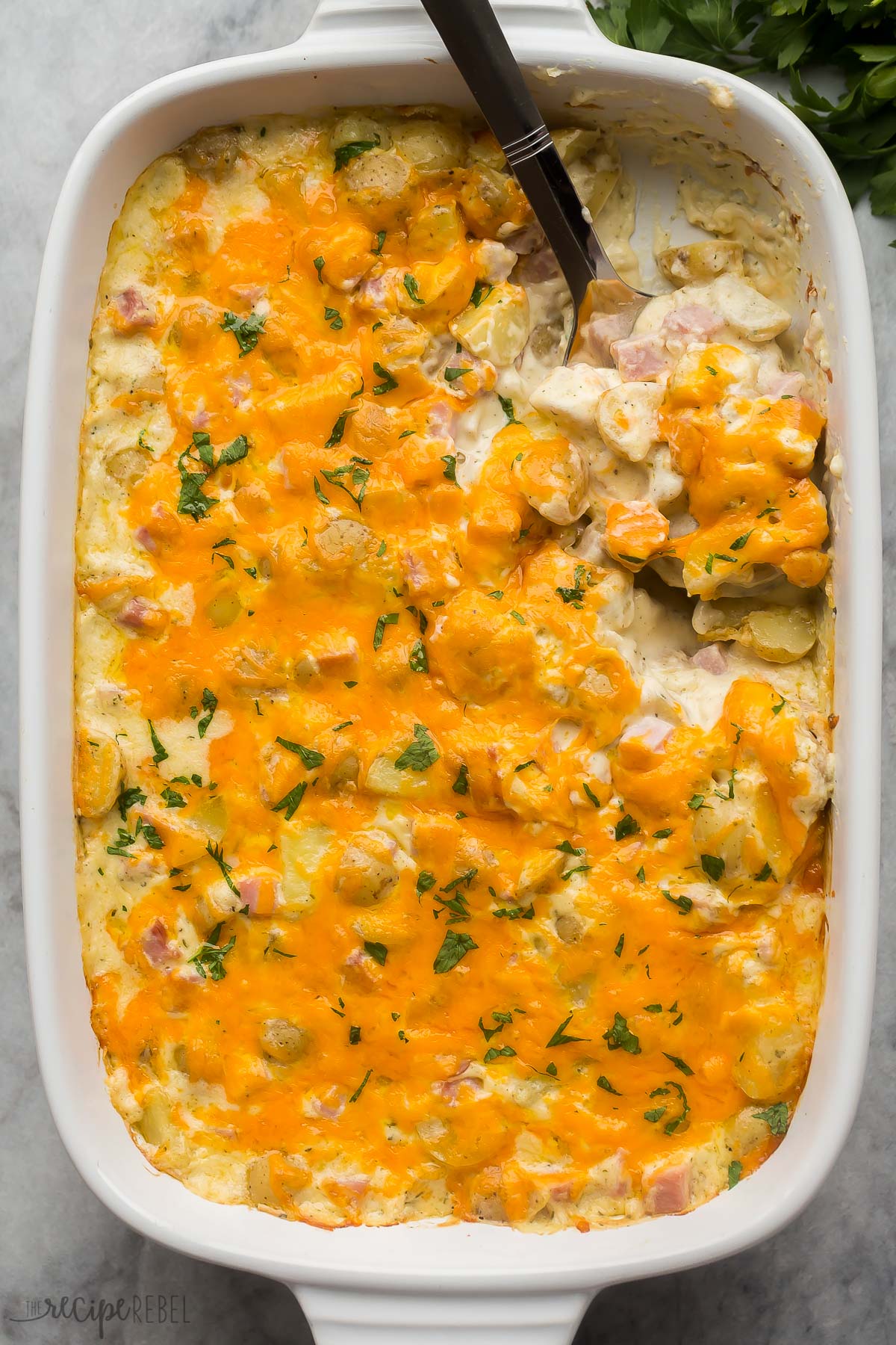 overhead image of pan of ham and potato casserole with spoon stuck in