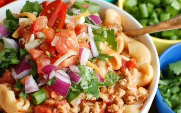 A bowl of turkey taco pasta topped with salsa.