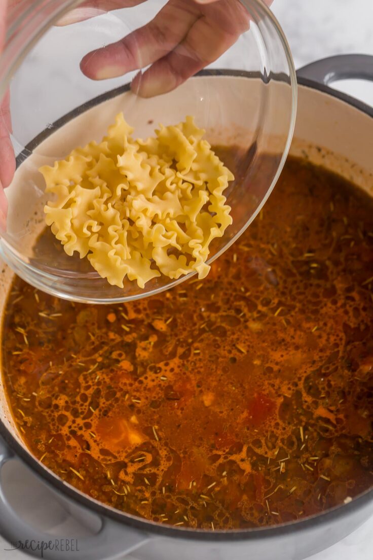 dry pasta noodles being added to lasagna soup