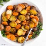square image of roasted potatoes and carrots in a bowl with a spoon.