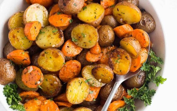 square image of roasted potatoes and carrots in a bowl with a spoon.