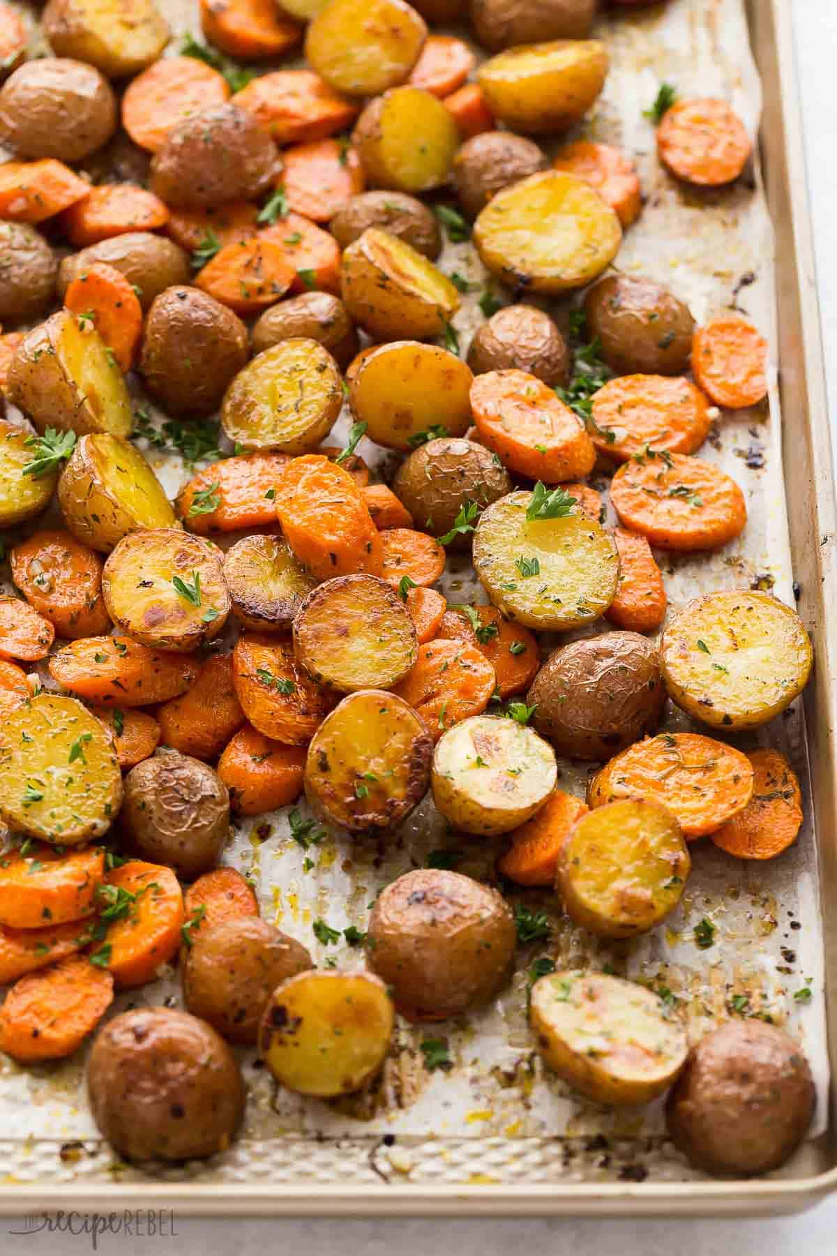 roasted potatoes and carrots on a sheet pan covered in parchment paper.