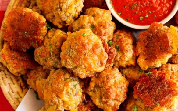 A basket of sausage balls with a cup of marinara