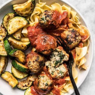 Spinach and feta turkey meatballs served over pasta with zucchini.