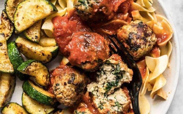 Spinach and feta turkey meatballs served over pasta with zucchini.