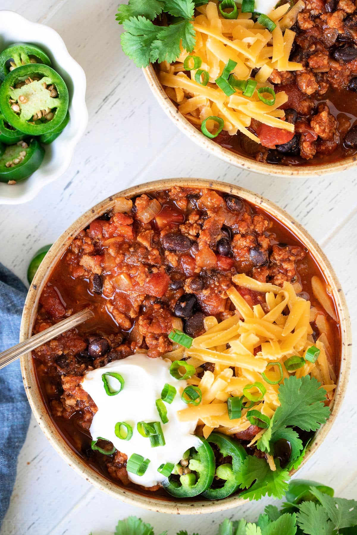 A bowl of turkey chili topped with shredded cheese and sour cream.