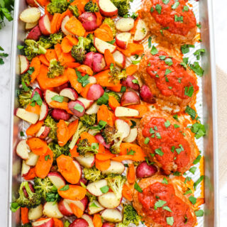Baked mini turkey meatloaf on a baking sheet with vegetables.