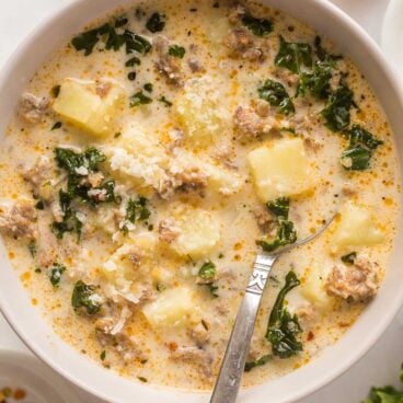 close up image of zuppa toscana in bowl with spoon