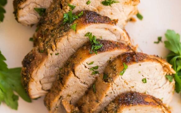 close up image of sliced air fryer pork tenderloin with fresh parsley